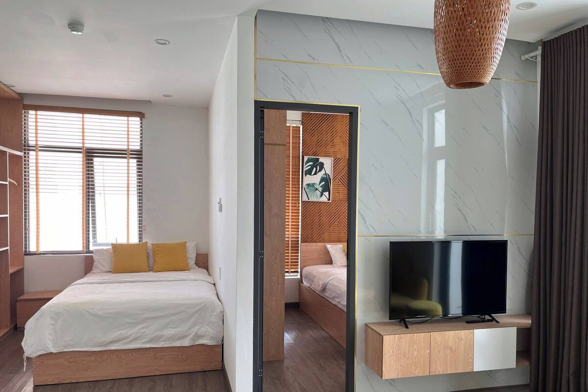 Un dormitorio moderno con una cama, un televisor y un armario de madera.