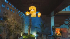 A modern interior with hanging wicker lamps, a stone wall with small windows, and a small altar with plants. - The H House Quy Nhơn (Quy Nhon)