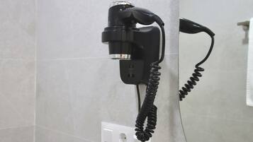 Un teléfono negro sujeto a la pared con un cable enrollado.