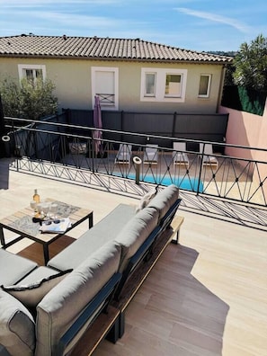 Terraço no telhado com piscina, área de estar externa e vista de um edifício com telhado em azulejos.