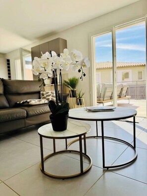 Uma sala de estar moderna com um sofá, uma mesa de centro e uma orquídea em vaso.