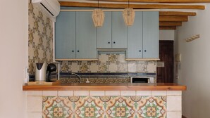 Een keuken met blauwe kastjes, een betegelde spatwand en een houten aanrecht.