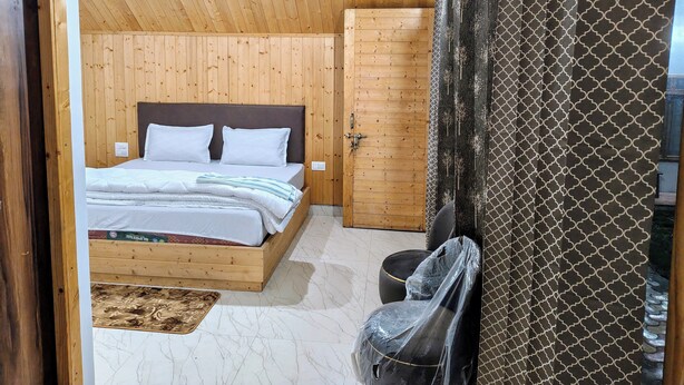 Een slaapkamer met houten lambrisering, een bed, een kledingkast en een stoel.