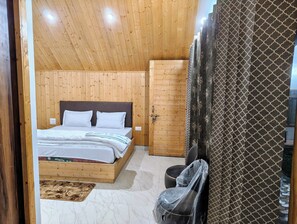 A wooden-paneled bedroom with a bed, a wardrobe, and a chair. - Blue Sheep Resort & Restaurant  (Dunda)