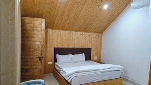 Een slaapkamer met een houten plafond, een bed met witte beddengoed en een houten hoofdbord.