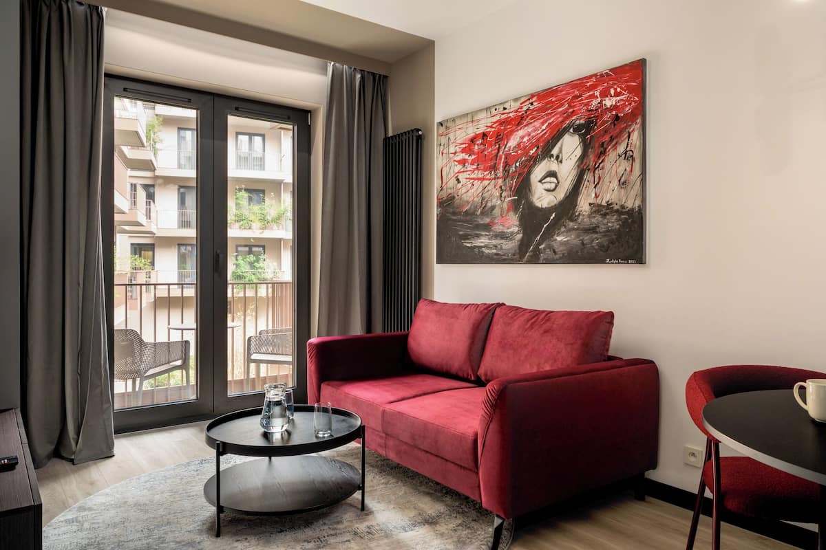 A modern living room with a red sofa, a round coffee table, and a view of an outdoor balcony.