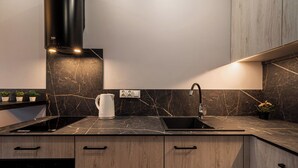 Una cocina moderna con encimera negra, estufa integrada, un lavamanos y armarios de madera.