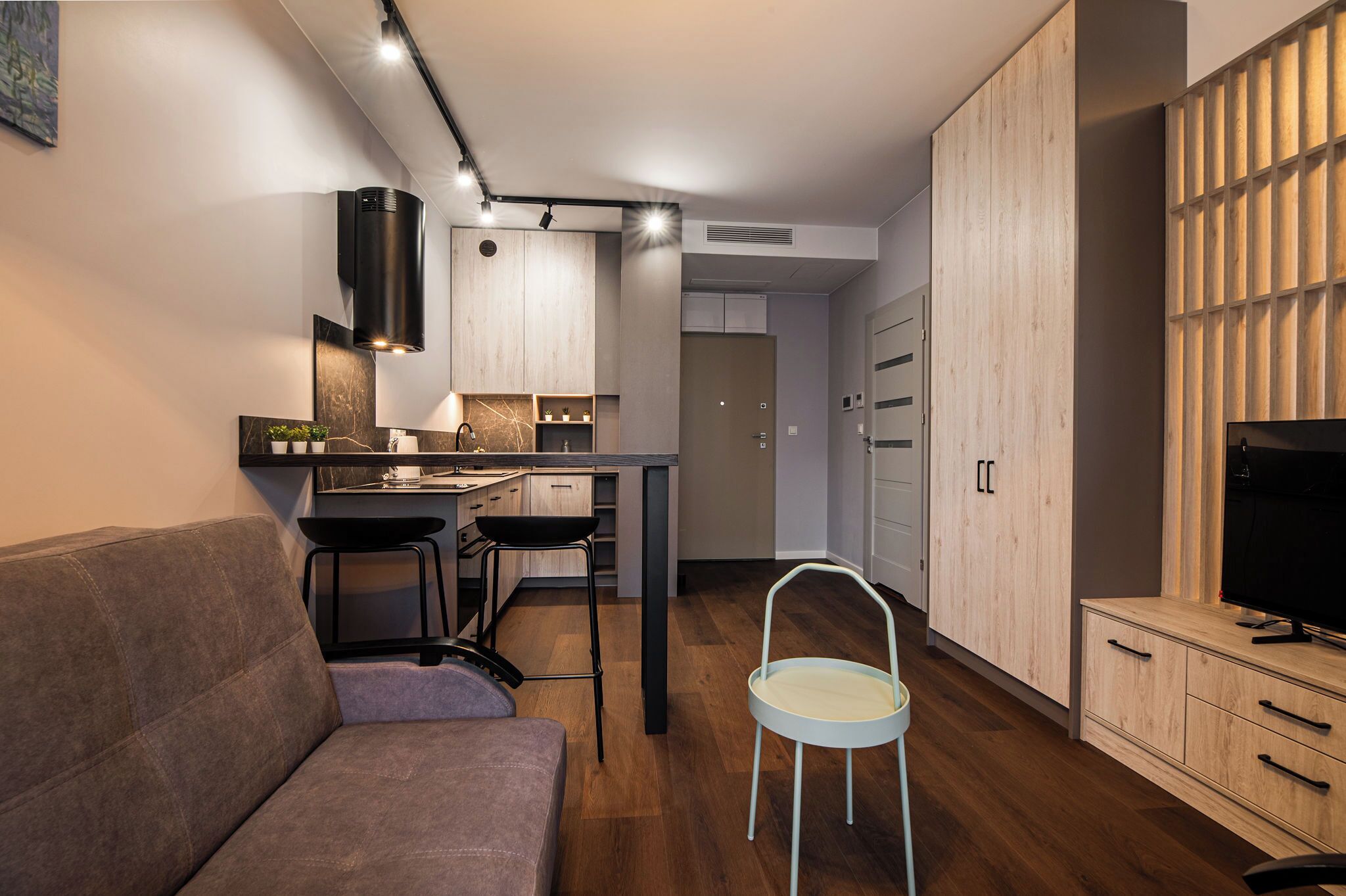 Una sala de estar moderna con un sofá, un comedor con cocina y un mueble para la televisión.