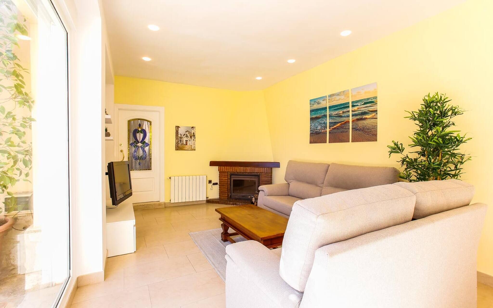 A living room with a sofa, a fireplace, a television, and a painting on the wall.