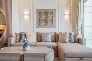 A modern living room with a sectional sofa, a round coffee table, and decorative pillows. - Luxury branded apartment in Dubai Creek Harbour with stunning Creek Beach view. (Dubai)