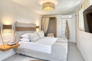 Een slaapkamer met een bed, nachtlampjes, een hangende macramé wanddecoratie, een ladder en een raam met gordijnen.