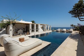 A poolside area with a stone building, outdoor seating, and a view of the sea. - Villa Emera with pool and view - My Rental Homes (Páros)