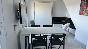 A modern kitchen with a white countertop, black chairs, and a dining table.