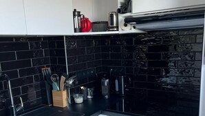 A modern kitchen with black and white cabinetry, a black countertop, and a black backsplash.