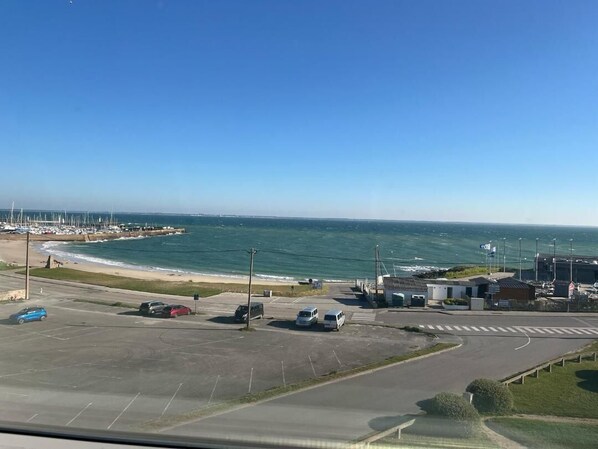 A coastal parking area with a view of the sea and a marina.