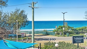 A coastal road with a sign for 'Talisman on Broadbeach' and a view of the ocean. - Sun-Kissed Escape - Broadbeach Gem (Gold Coast)