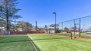 An outdoor tennis court with a net, surrounded by a fence and trees. - Sun-Kissed Escape - Broadbeach Gem (Gold Coast)
