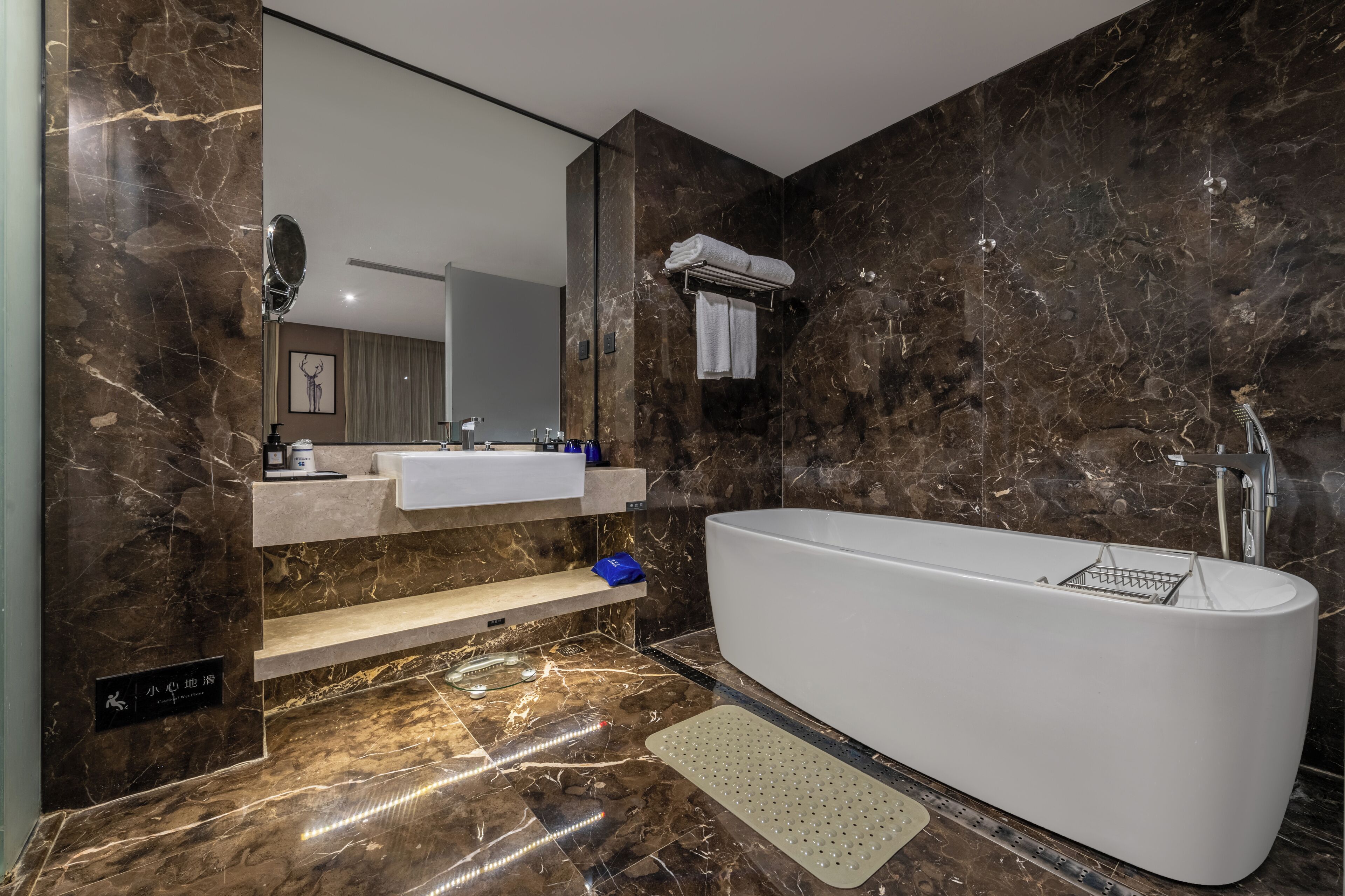 A modern bathroom with a freestanding bathtub, a large mirror, and a vanity with a towel rack.