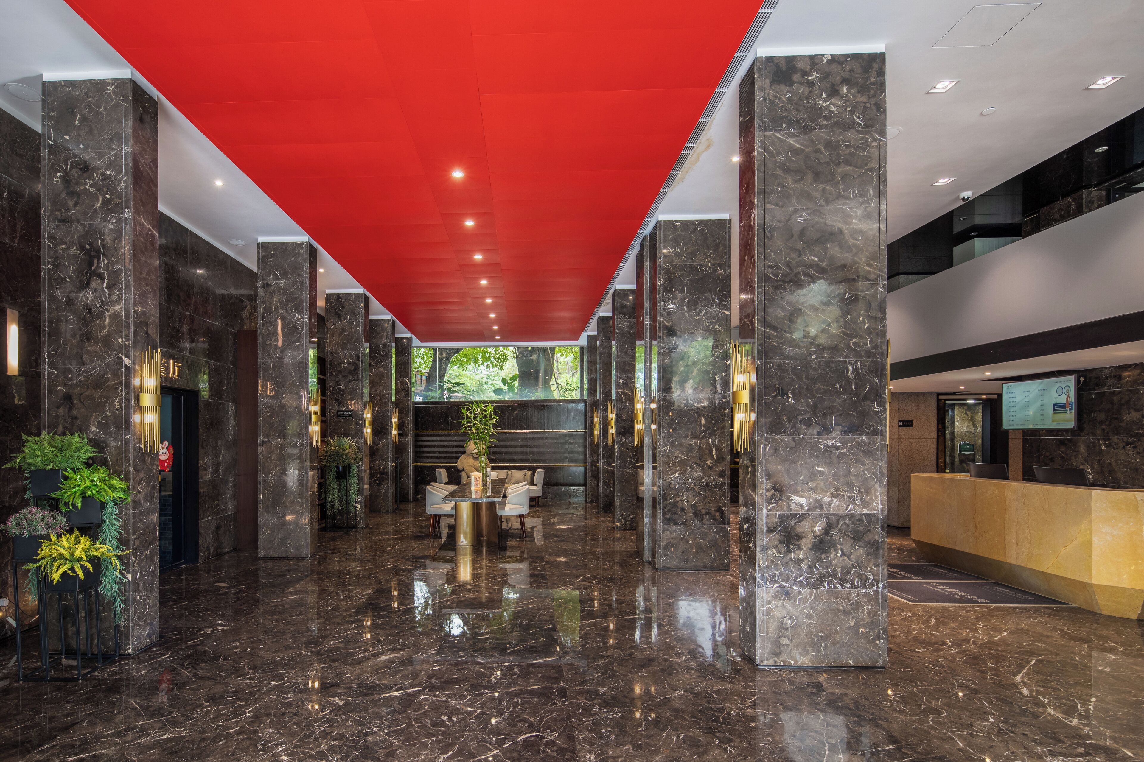 A modern lobby with marble floors, a reception desk, and a red ceiling.