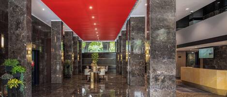 A modern lobby with marble floors, a reception desk, and a red ceiling.