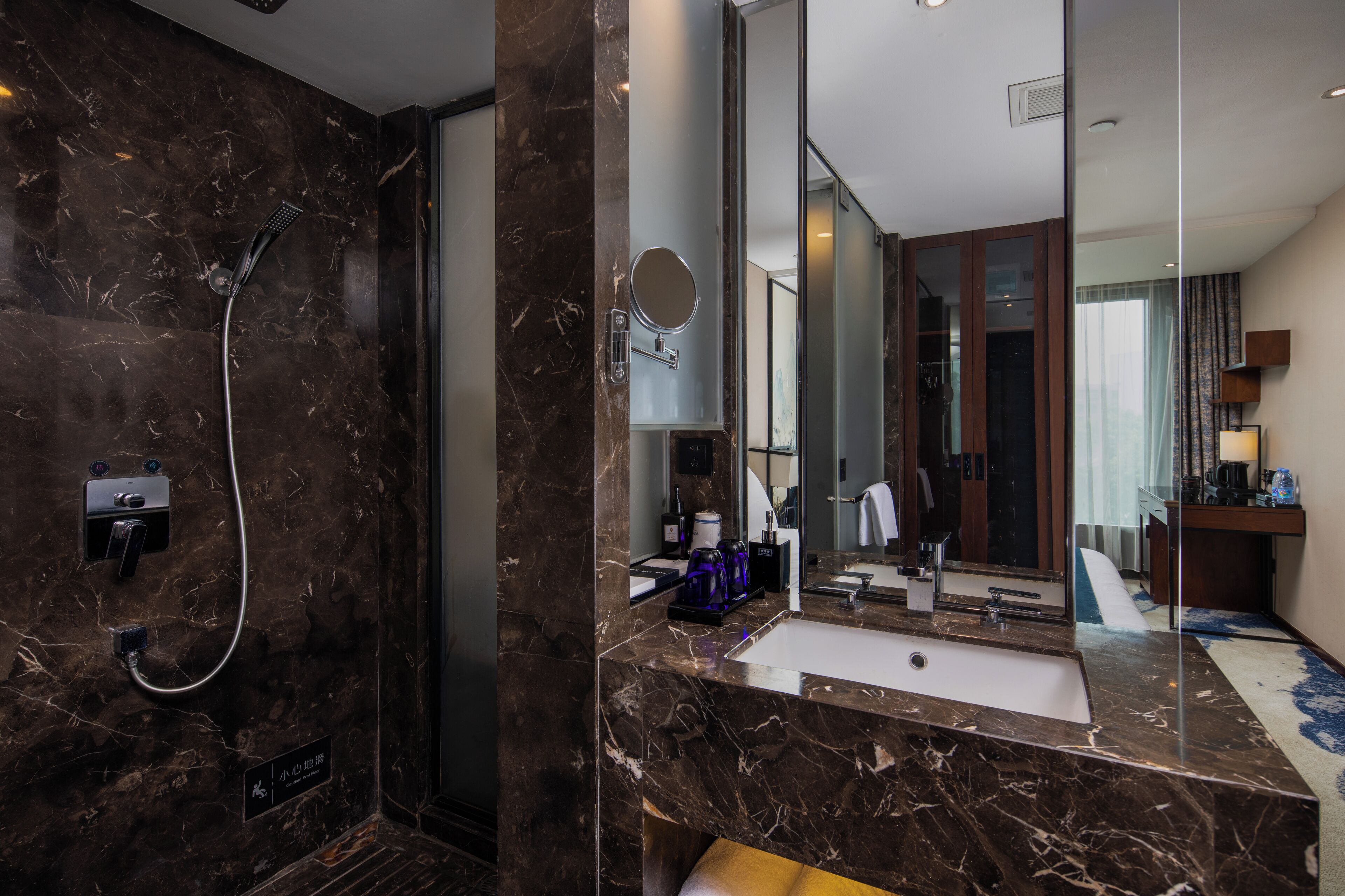 A modern bathroom with a marble sink, a handheld showerhead, and a large mirror.