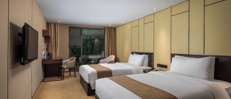 A hotel room with two beds, a desk, a chair, and a TV.