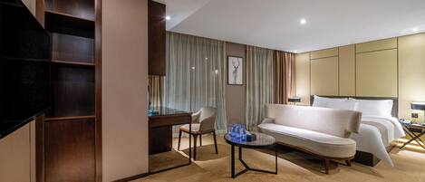 A hotel room with a bed, a sofa, a desk, and a television.