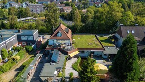 Ein Wohngebiet mit einem Haus, das ein geneigtes Dach, Solaranlagen und einen kleinen Garten hat.