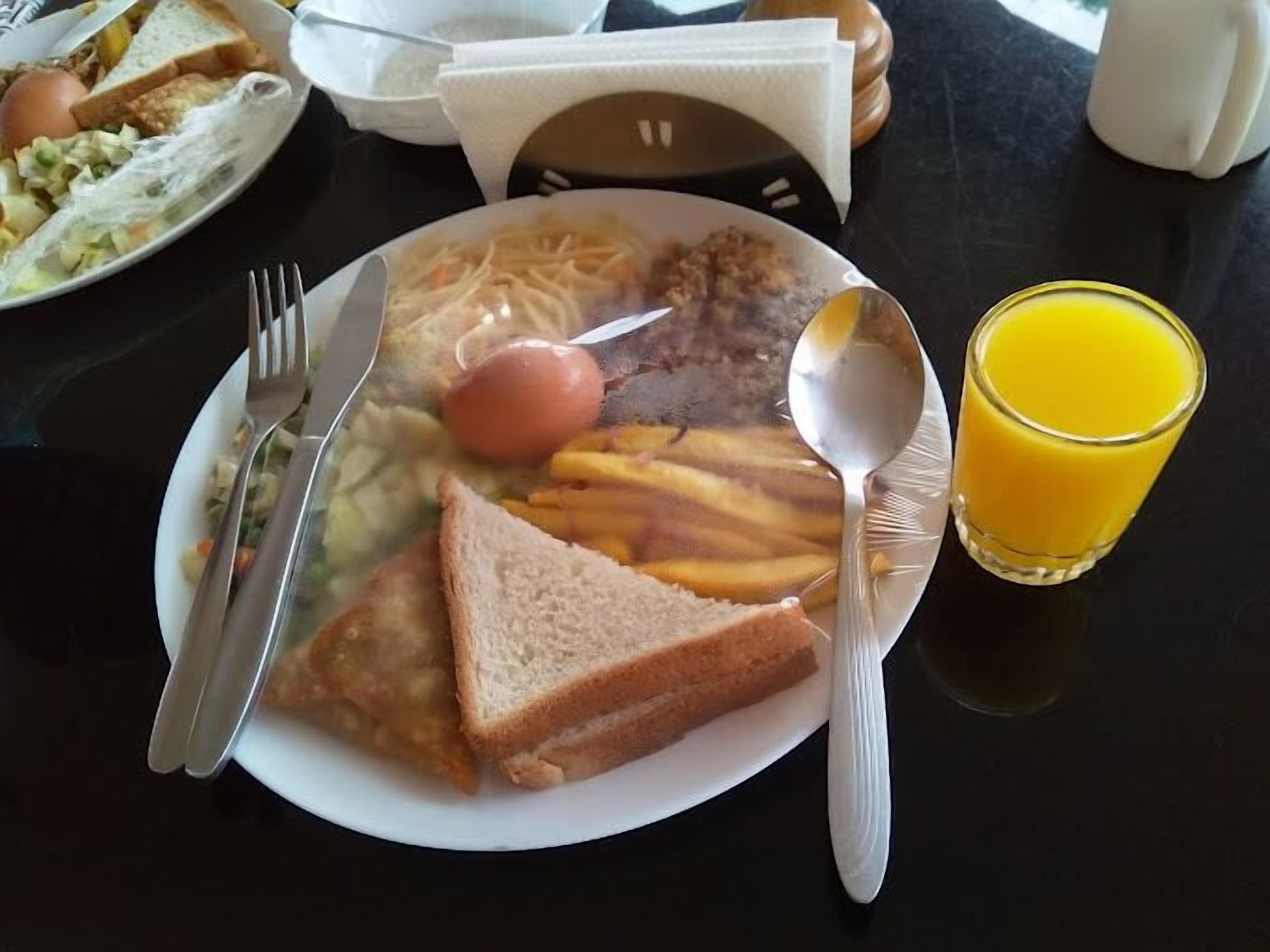 Een ontbijtbord met eieren, toast en friet, plus een glas sinaasappelsap.
