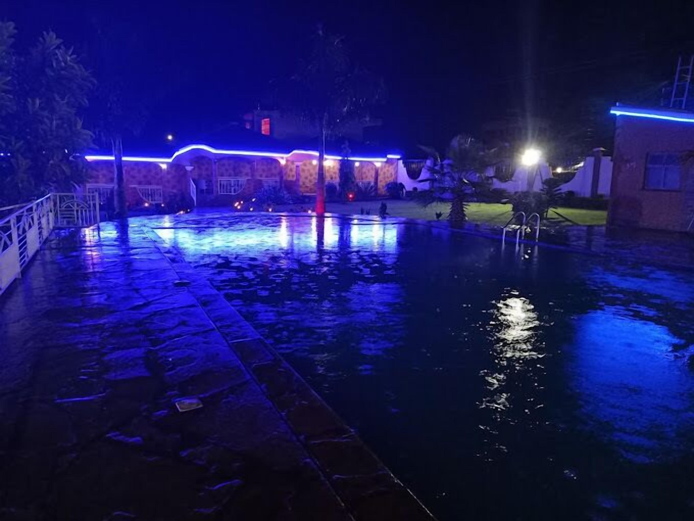 Area piscina illuminata di blu con pavimento in pietra, di notte.