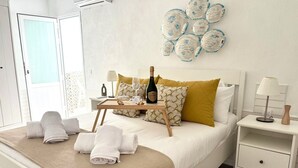 A neatly made bed with a bottle of champagne, a tray with glasses, and towels.