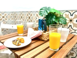 Un desayuno con un croissant, jugo de naranja y leche sobre una mesa de madera.