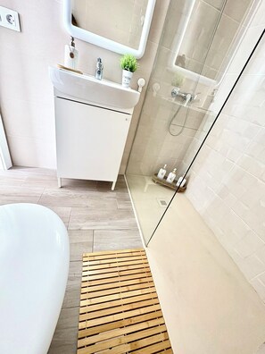 Un baño moderno con lavamanos, espejo y ducha blancos.
