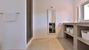 Un baño moderno con un espejo grande, un lavamanos y estantes para almacenamiento.