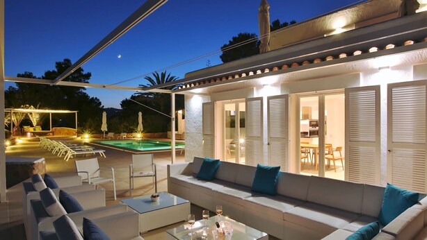 Un área de estar exterior con piscina, sillones reclinables y una mesa de centro de vidrio.