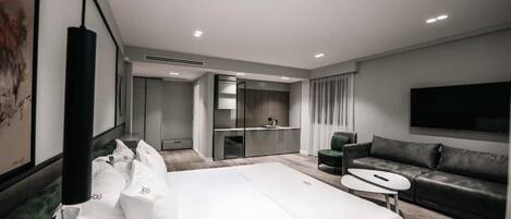 A modern hotel room with a large bed, a sofa, a TV, and a small table.