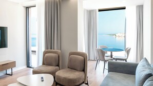 Ein modernes Hotelzimmer mit Balkon, einer Sitzecke, einem Couchtisch und einem Essbereich mit Stühlen.