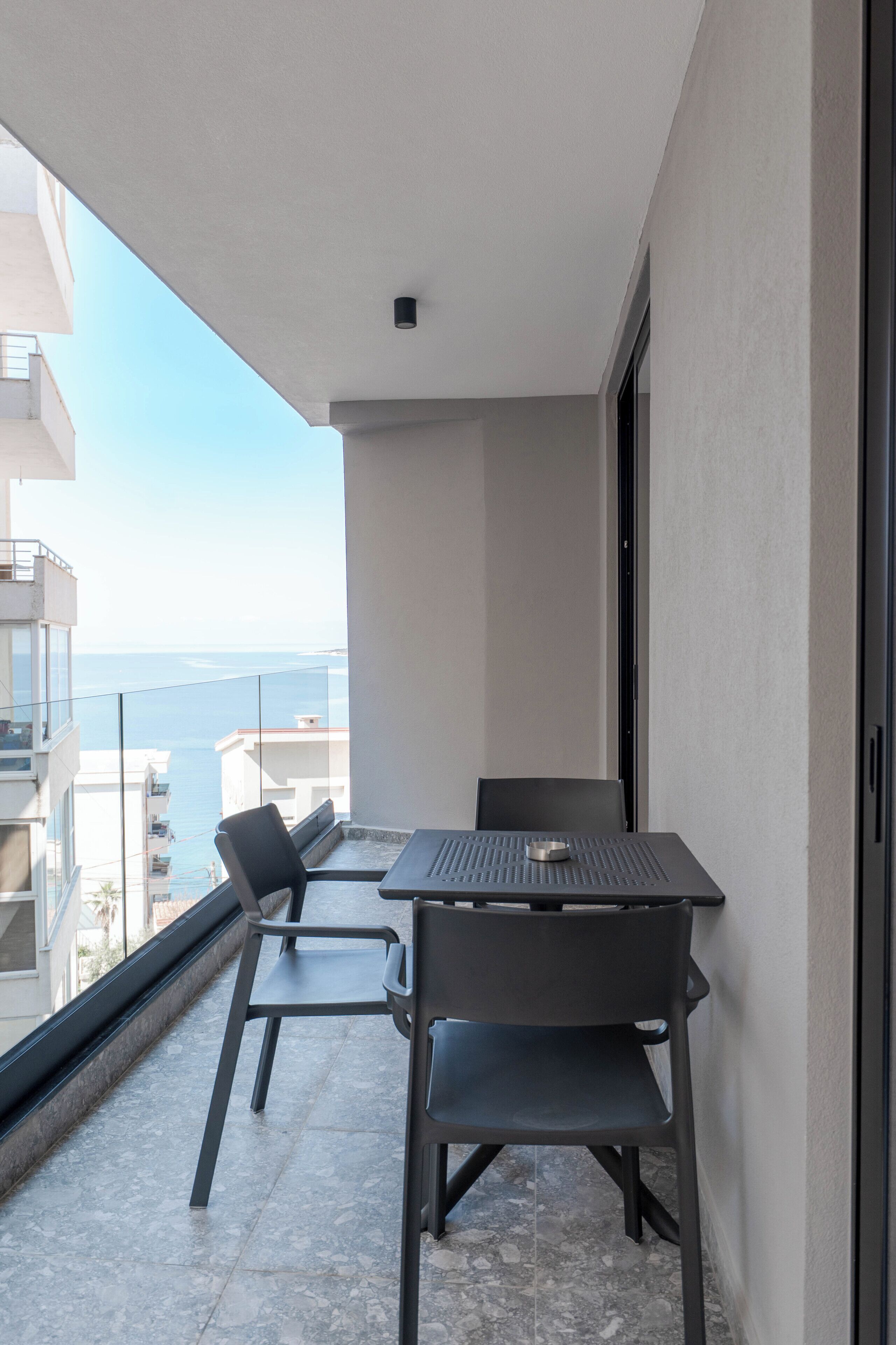 Un balcón con mesa y sillas, con vistas a la ciudad y al mar.