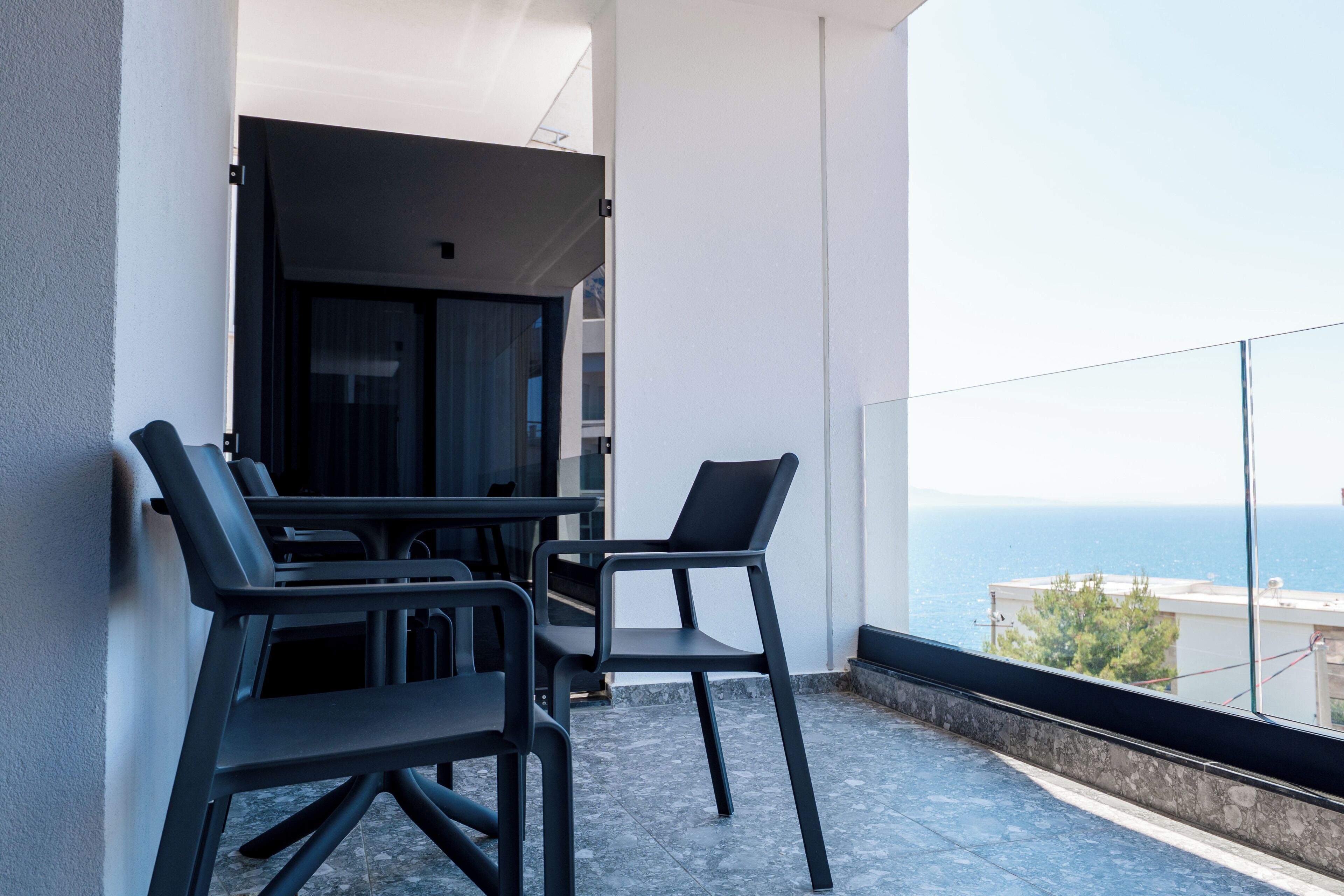 Un balcon avec deux chaises et une table, donnant sur une étendue d’eau.