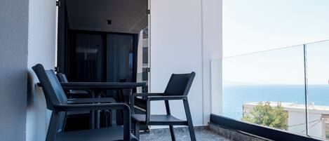 Un balcon avec deux chaises et une table, donnant sur une étendue d’eau.