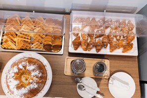 A buffet with waffles, croissants, and a cake. - Boe Luxury Hotel (Sarande)