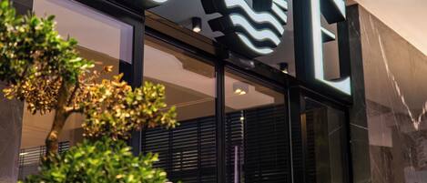 Une façade moderne avec une enseigne « BOE » bien visible, une entrée en verre et un arbre bien entretenu devant le bâtiment.