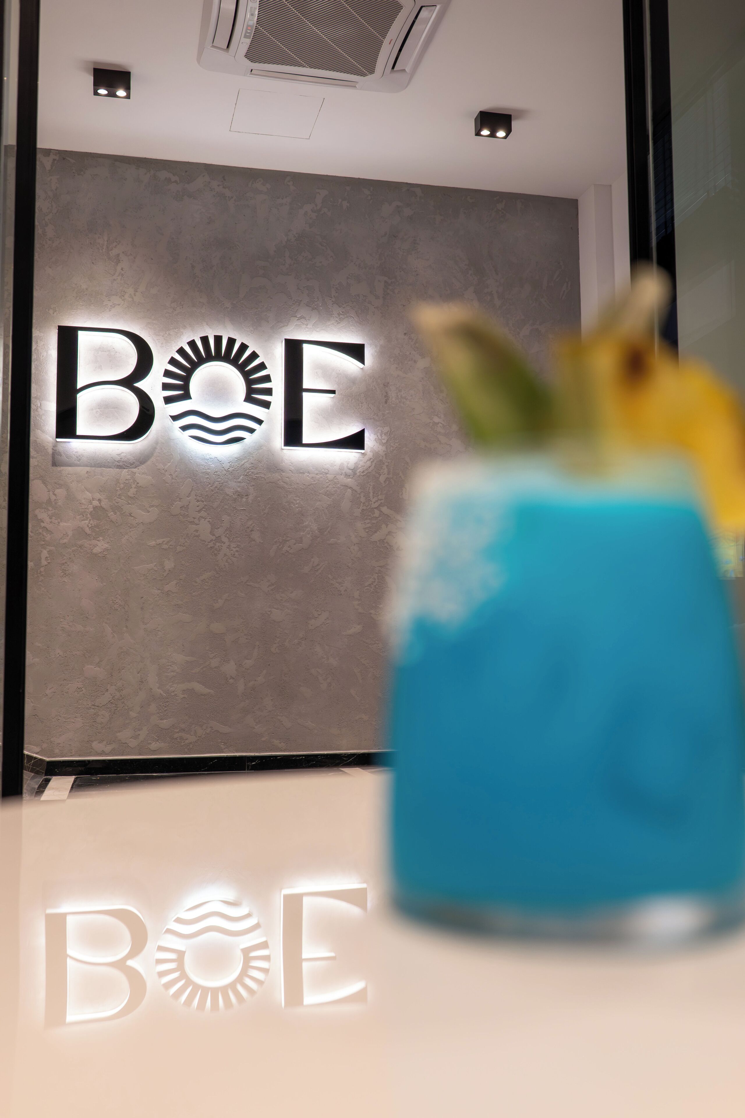 A wall with the illuminated text 'BOE' and a blue object in the foreground.