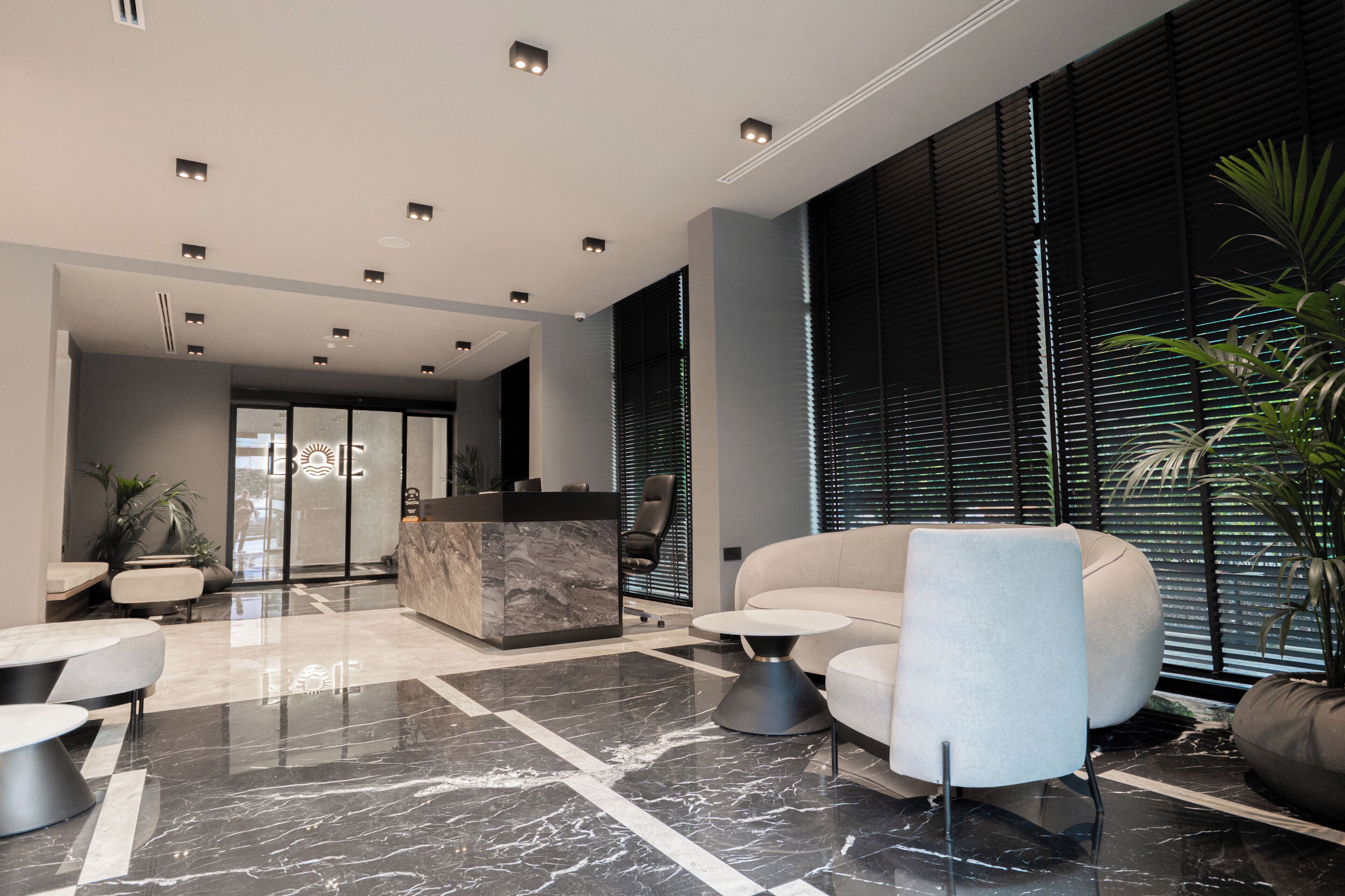 Eine moderne Lobby mit einer Rezeption, einer Sitzecke und großen Fenstern.