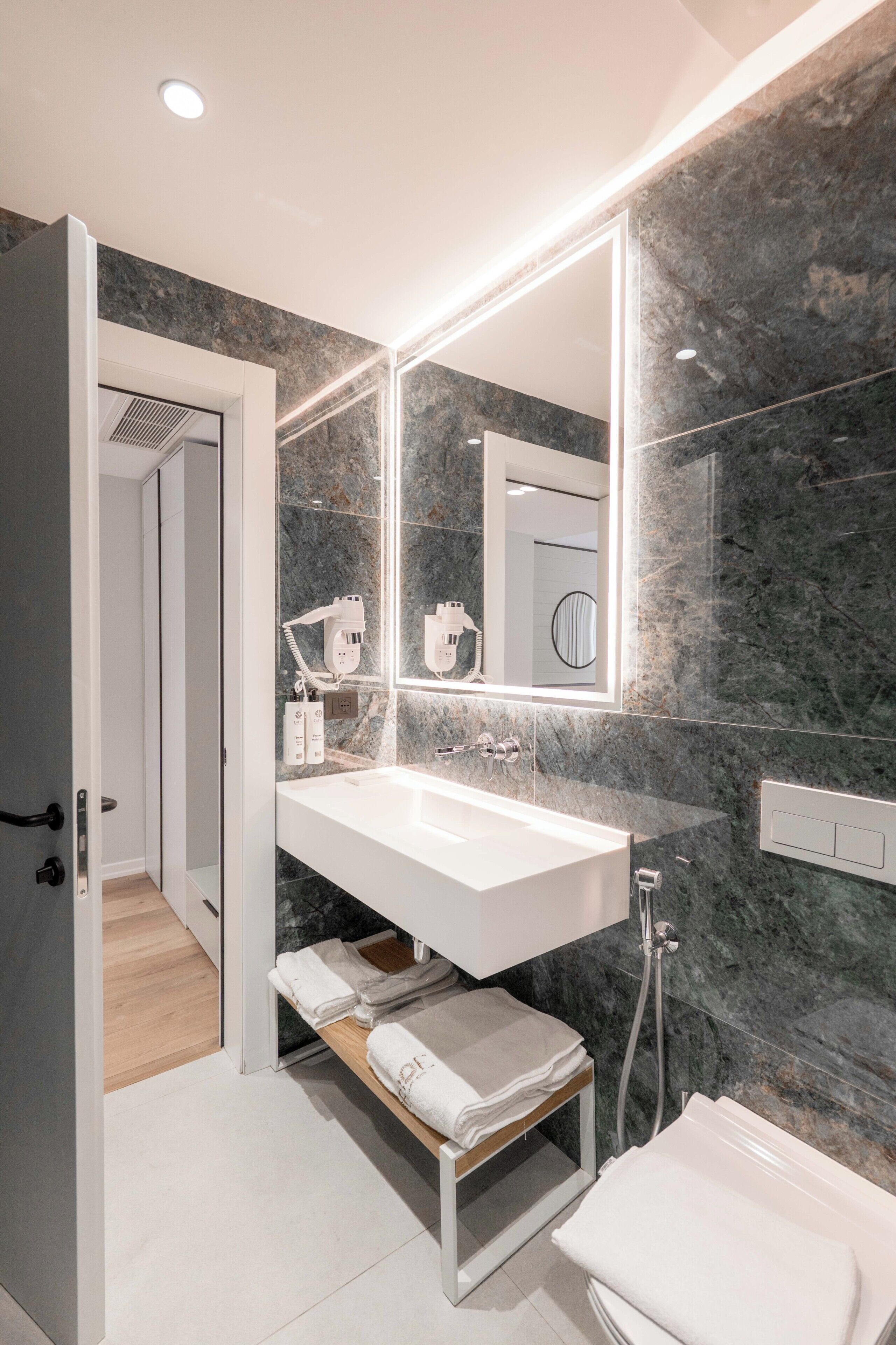 A modern bathroom with a white sink, a large mirror, and a shower.