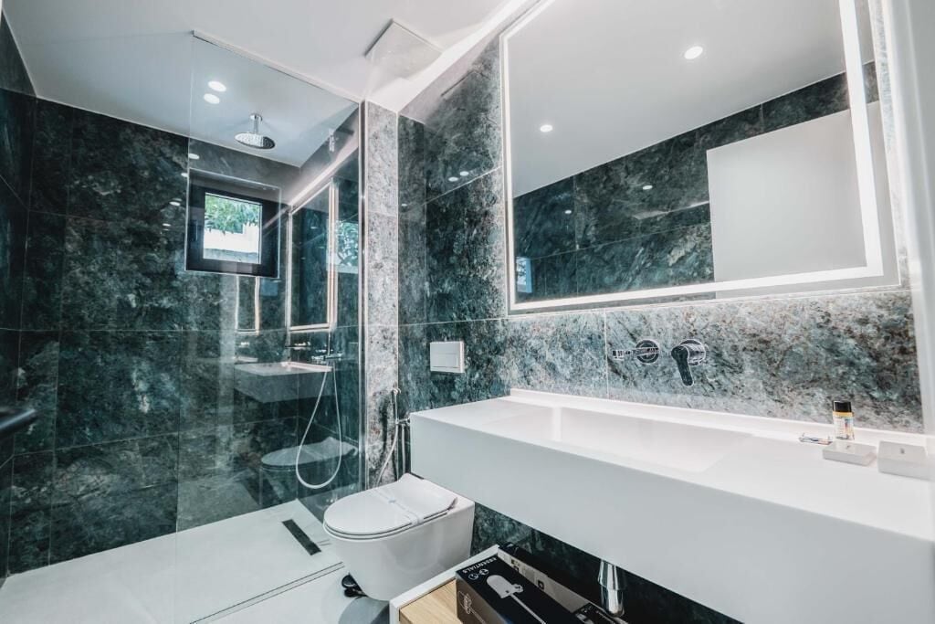 Un baño moderno con un espejo grande, un lavabo blanco y una zona de ducha.