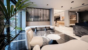 Eine moderne Lobby mit Sitzbereichen, einem Empfangsbereich und großen Fenstern.