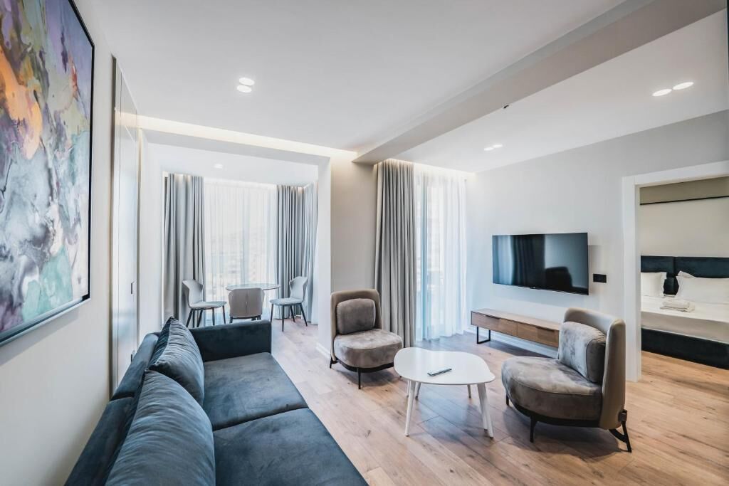 A modern living room with a sofa, armchairs, a coffee table, and a TV.