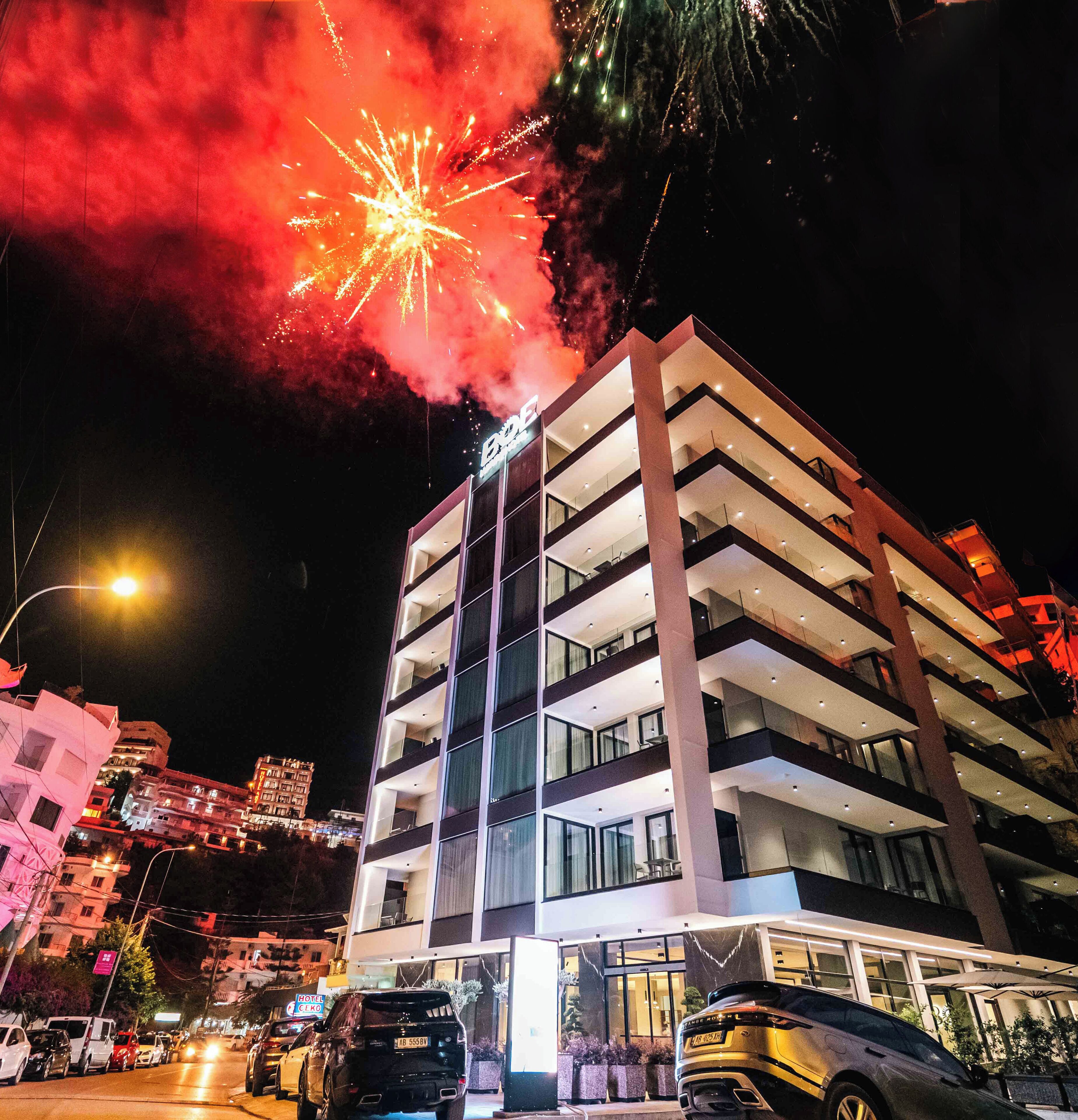 A multi-story hotel with a modern design, featuring balconies on each floor and a well-lit facade.