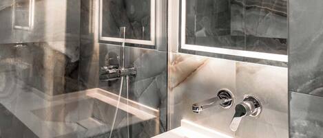 A modern bathroom with a glass-enclosed shower, a large mirror, and a white sink.